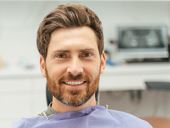 Bearded man sitting in dental chair smiling