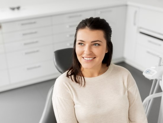 Woman in white sweater smiling in dental chair