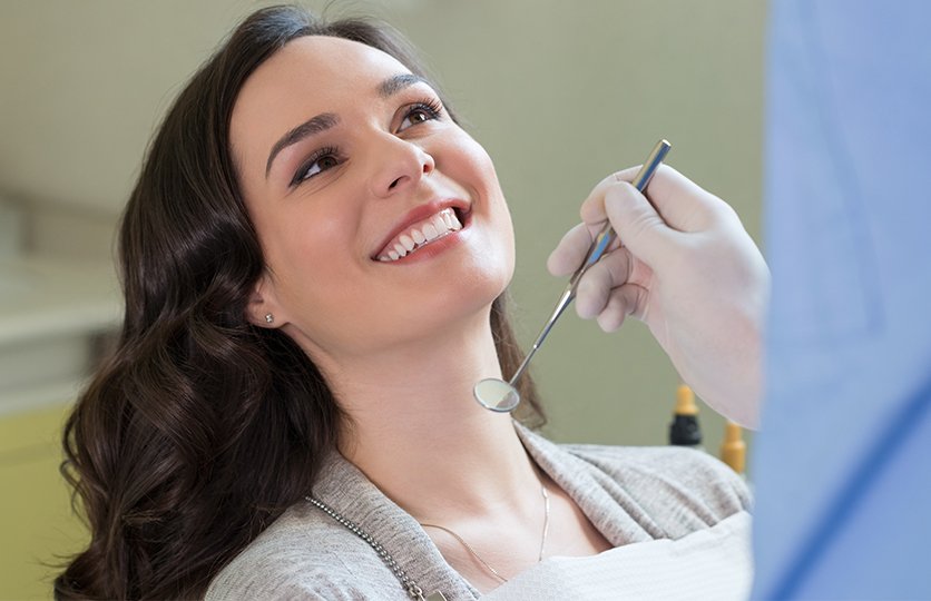 Dentist looking at patient's smile after in practice teeth whitening treatment