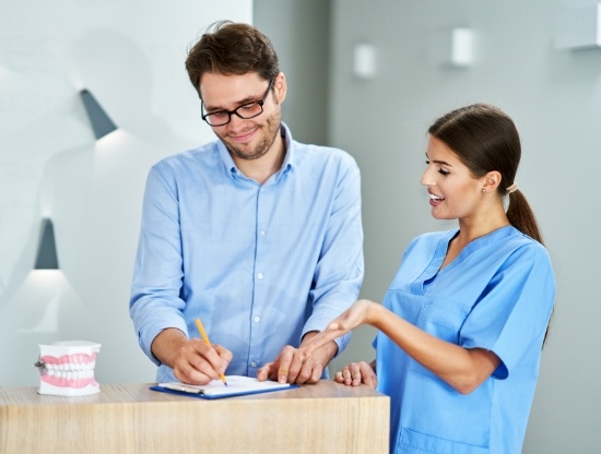 Dental team member showing a patient where to sign on a clipboard