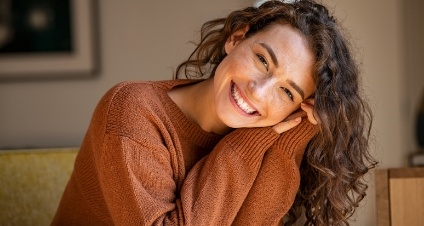 Woman in orange sweater smiling after receiving dental services in Rocky Hill