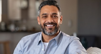 Smiling man in light blue collared shirt sitting on couch