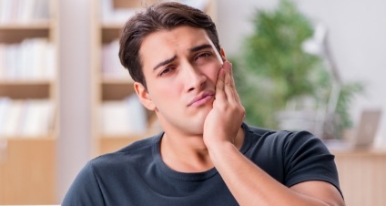 Young man frowning and holding his jaw