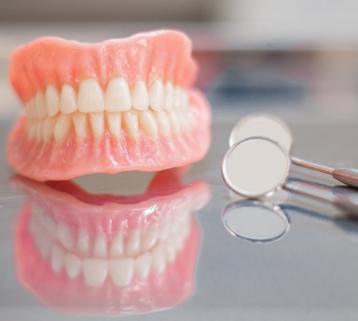 Closeup of hand holding dentures in Rocky Hill