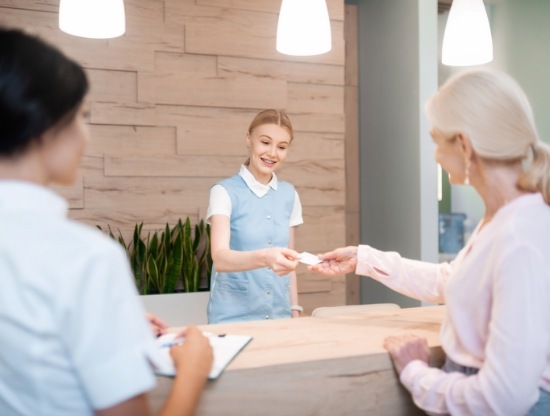 Dental patient handing a payment card to a receptionist at front desk
