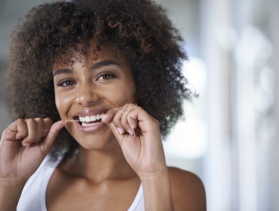Woman smiling while flossing her teeth