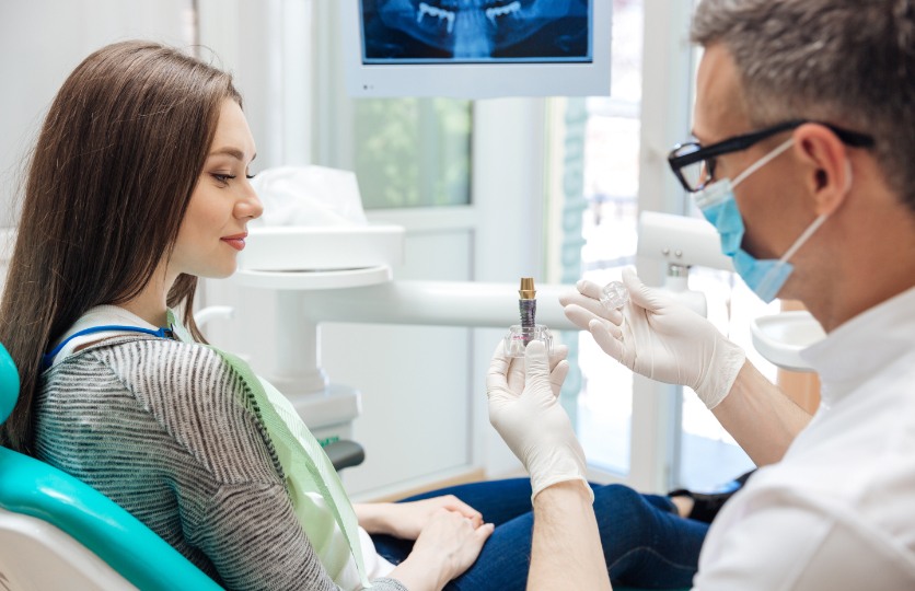 Dentist showing a dental implant model to dental patient