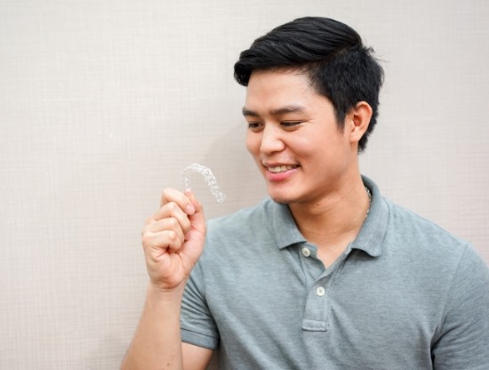 Young man holding a clear aligner