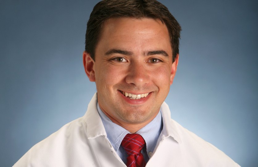 Doctor Scoles smiling waring a lab coat