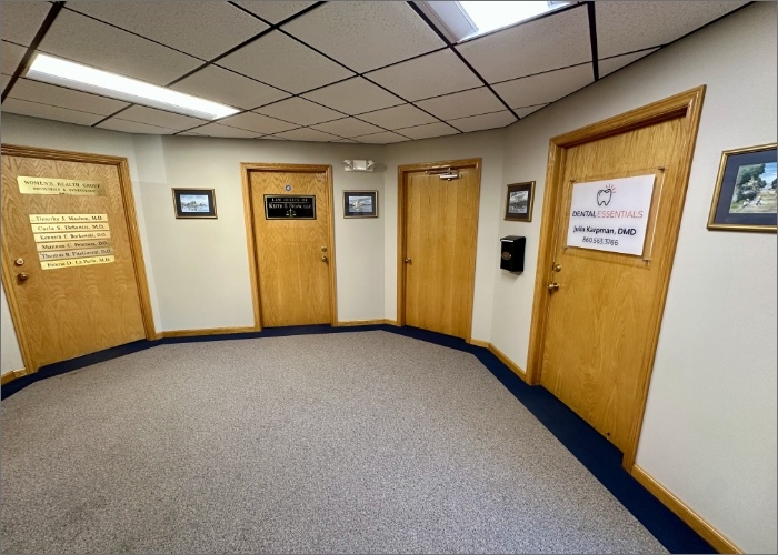 Inside the Dental Essentials building, a hallway with doors and decorative pictures lining the walls