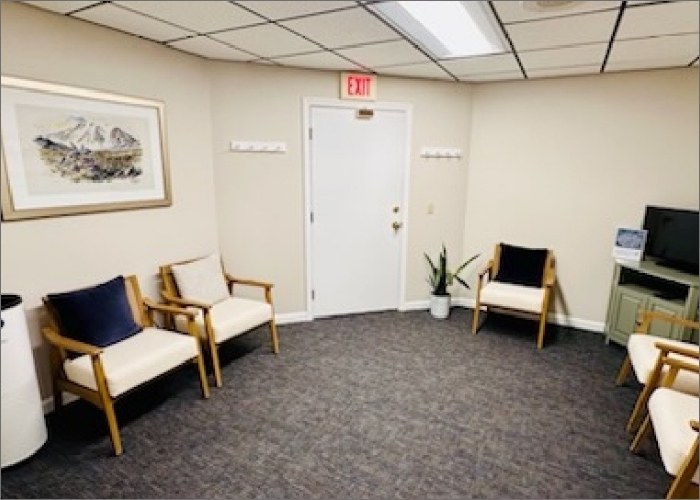 A waiting room inside Dental Essentials featuring chairs and a television for patients