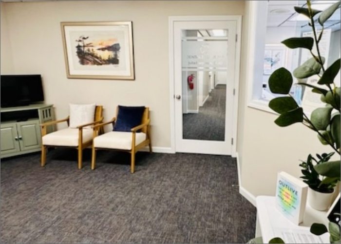 Inside Dental Essentials, a waiting room with comfortable chairs and a TV for entertainment.