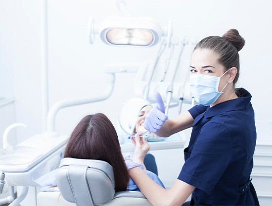 Dental team member standing next to patient, making thumbs-up gesture
