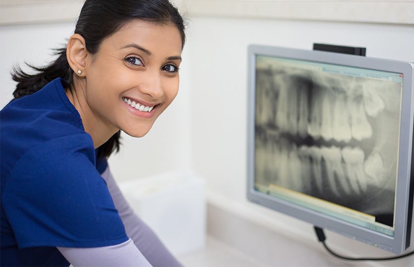 Dental team member looking at panoramic dental x-rays on chairside computer screen