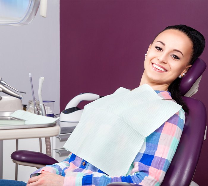 Woman sitting back in dental chair and smiling