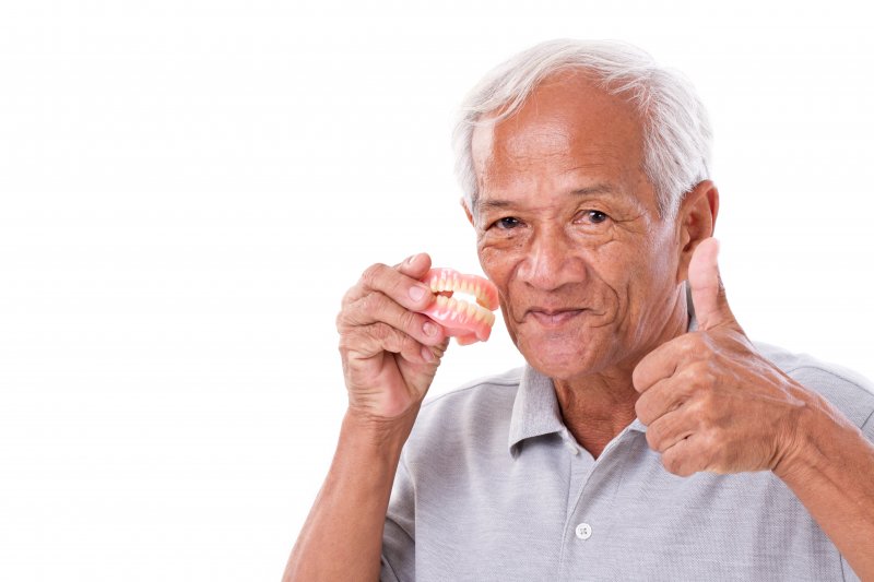 A senior man caring for dentures