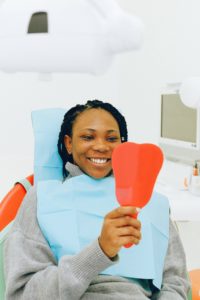 Smiling woman in dentist’s chair looking in mirror