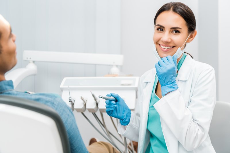 female dentist smiling while holding drill 