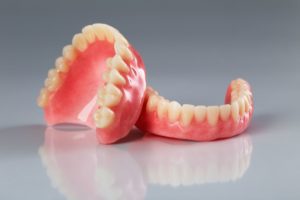 Set of dentures sitting on a reflective gray surface